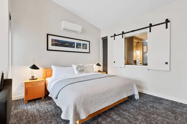 Modernes Hotelzimmer mit Doppelbett, Nachttischen und Schiebetüren am Fenster.