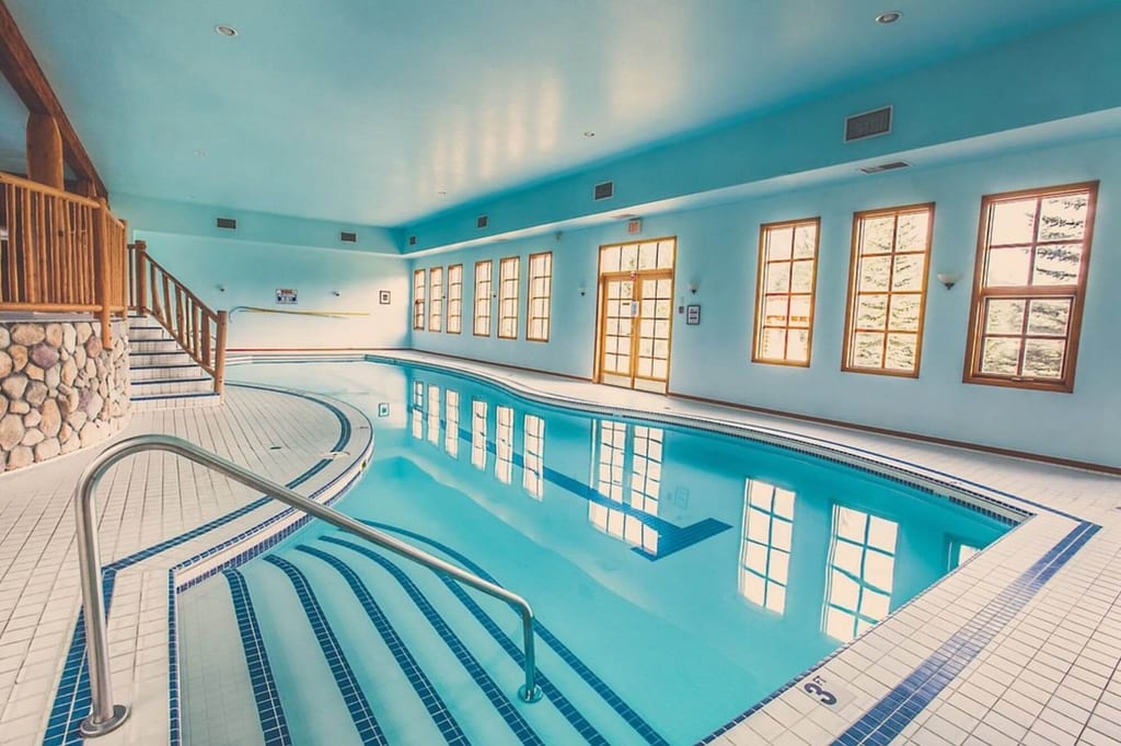 Hallenbad mit ruhigem, spiegelndem Wasser, Treppenstufen und Fensterlicht