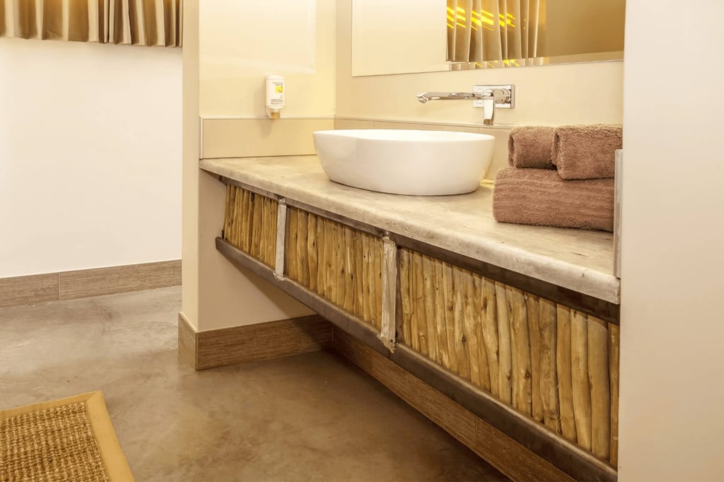 Badezimmer mit ovalem Aufsatzwaschbecken, Holzfront und gestapelten Handtüchern