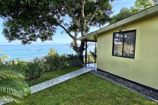 Gelbes Haus mit Hängematte im Garten und Blick auf ruhige See mit Booten