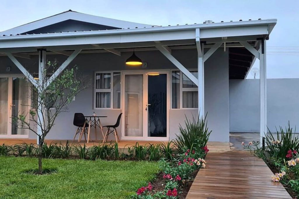 Vorderansicht eines Hauses mit Veranda, Gartenweg und warm beleuchteter Sitzecke.