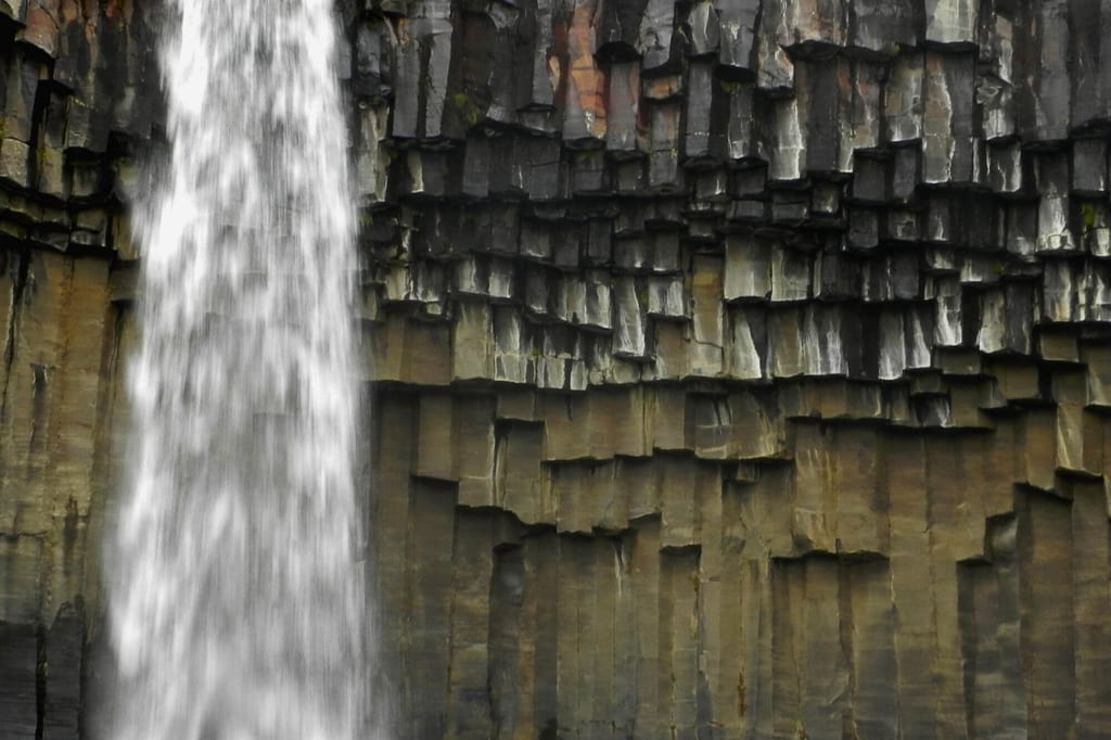 Wasserfall vor gestuften Basaltsäulen mit markanter, kantiger Struktur