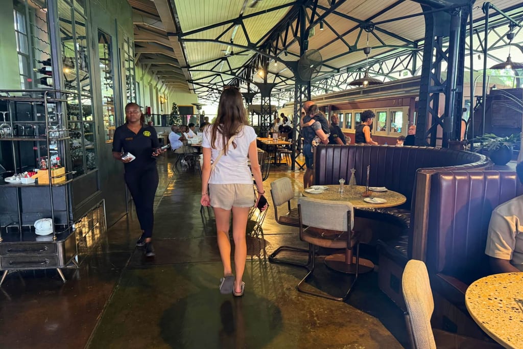 Blick ins belebte Restaurant, Frau in Shorts geht in den Gastraum, industrielle Innenarchitektur